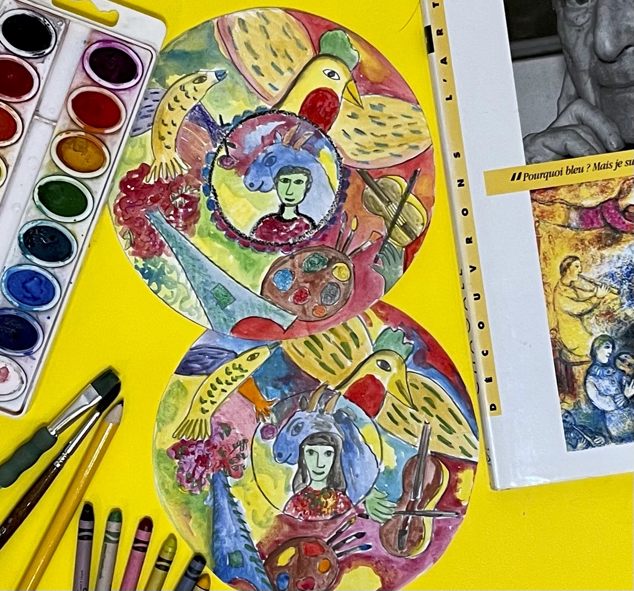 A colorful sketchbook page with watercolors, crayons, and pastels